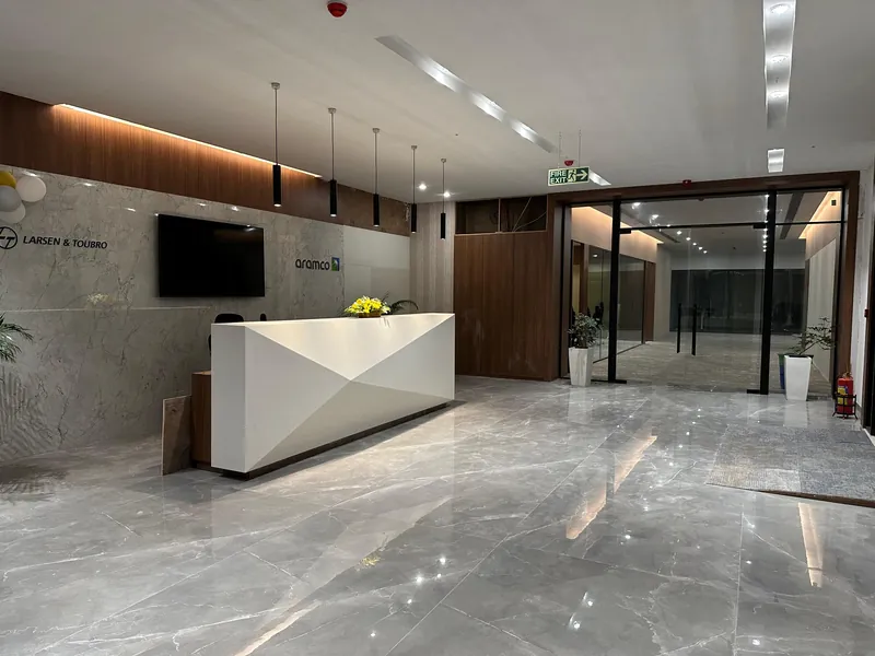Corporate reception lobby with faceted white desk, marble flooring and wood-clad feature wall.