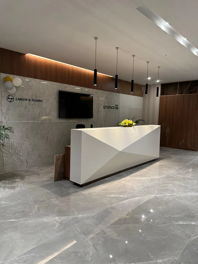 Reception desk with marble wall, branded signage and pendant lighting in a corporate lobby.