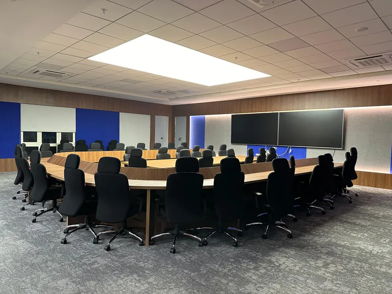 Large boardroom with U-shaped table, executive chairs and dual conferencing displays.