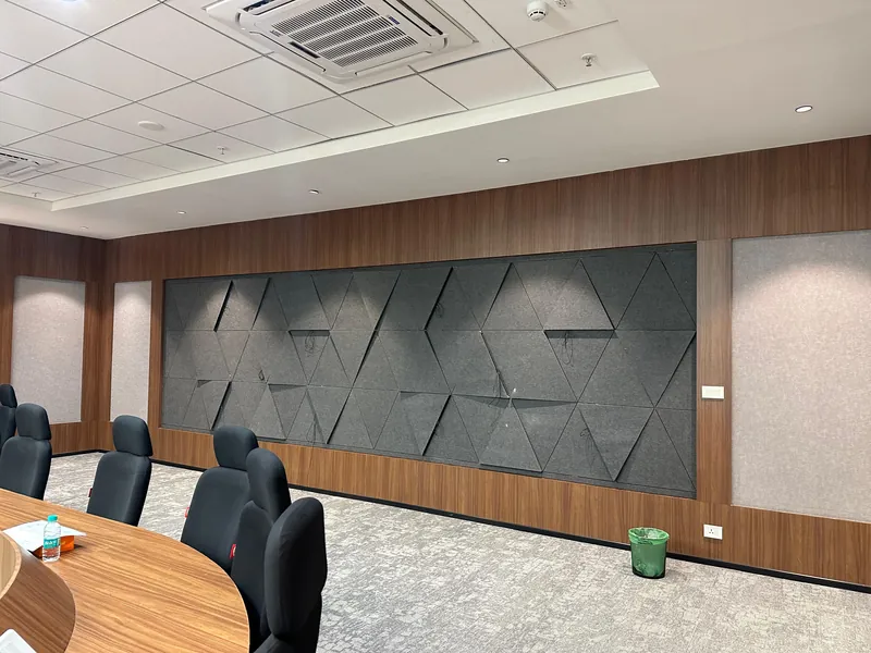 Meeting room with textured grey 3D acoustic feature wall and wood-paneled surrounds.