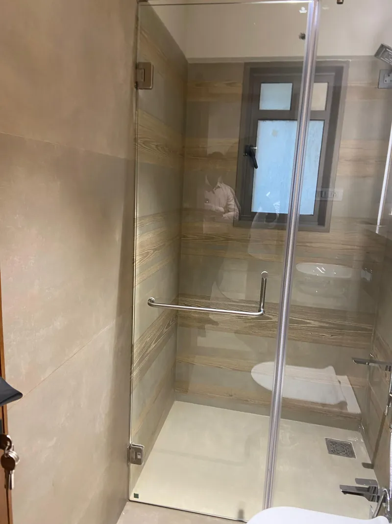 Contemporary bathroom with glass shower enclosure and wood-grain tiled walls.
