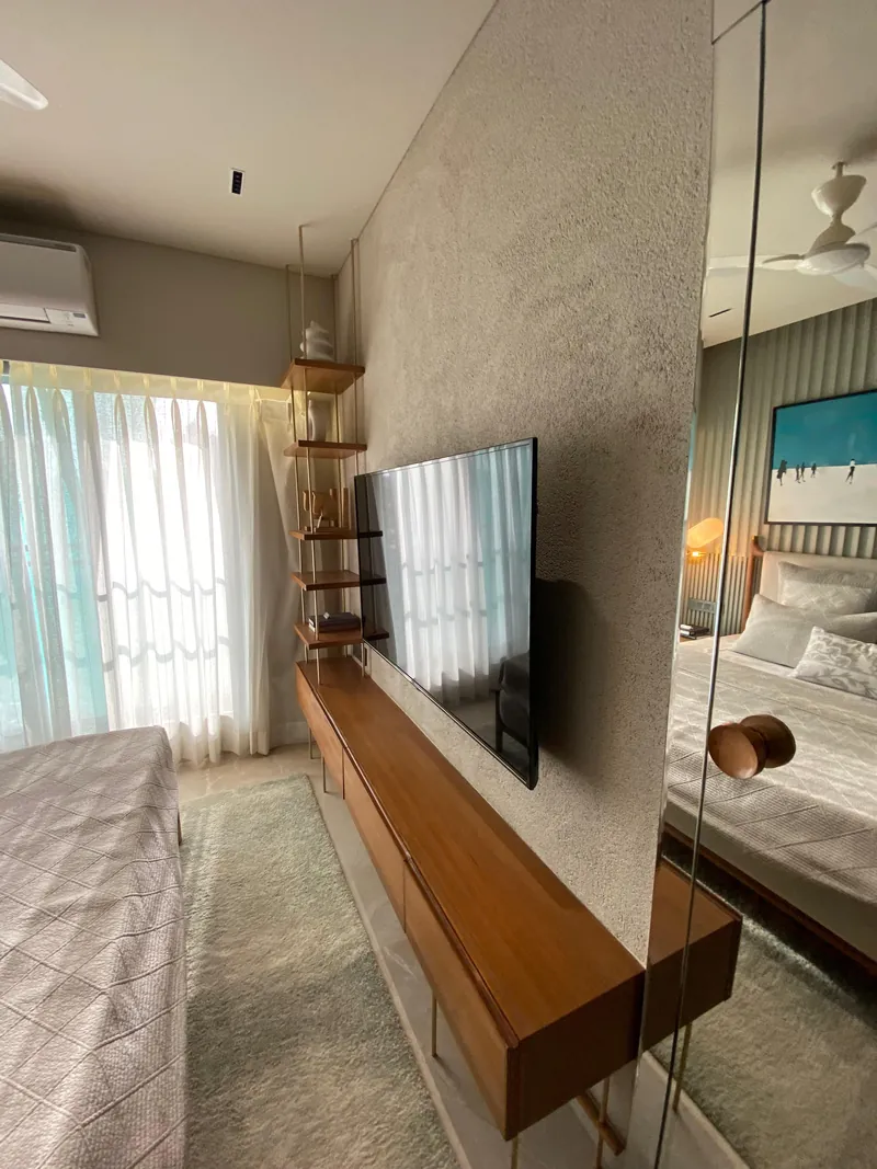 Modern bedroom TV unit with wood console, open shelving, and textured plaster wall.
