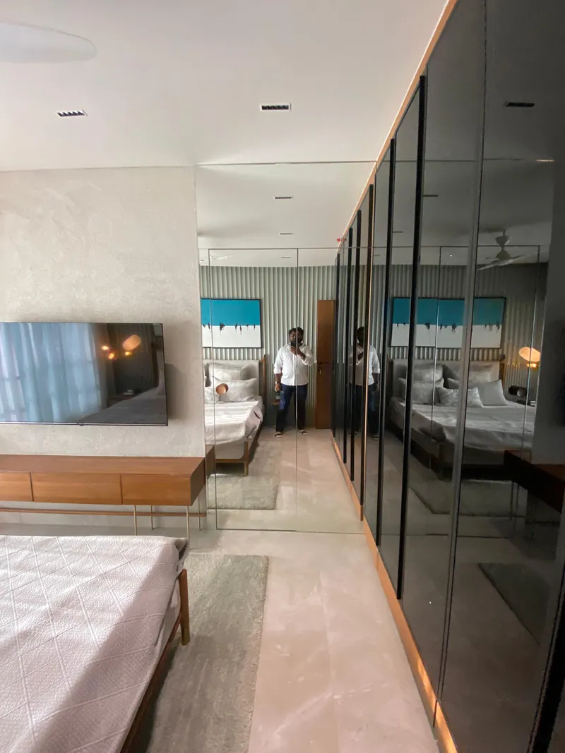 Bedroom dressing area with full-height mirrored glass wardrobe and wood TV console.