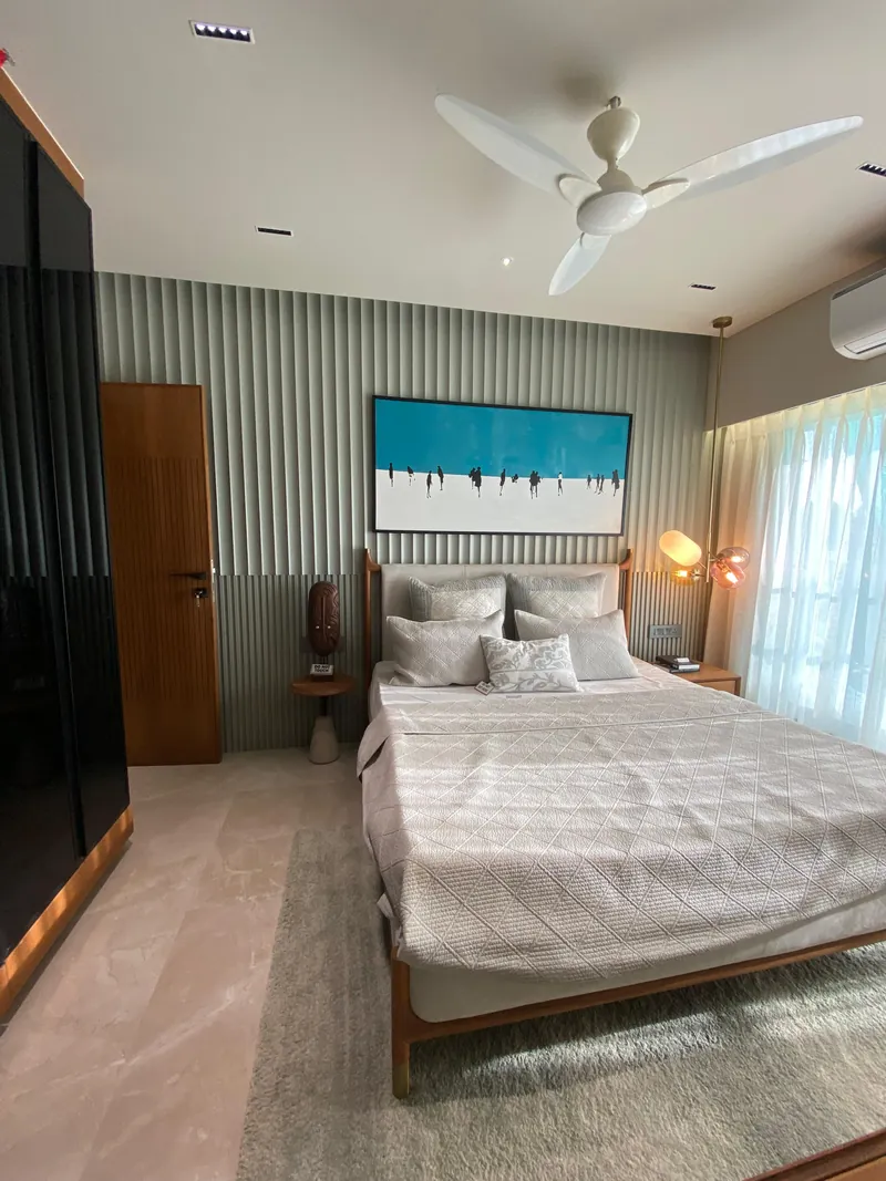 Modern bedroom with fluted wall, framed artwork, and wood-framed double bed.
