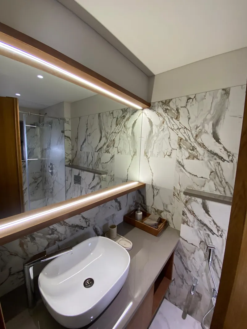 Luxury bathroom with vessel sink, marble walls, and backlit wood-framed mirror.