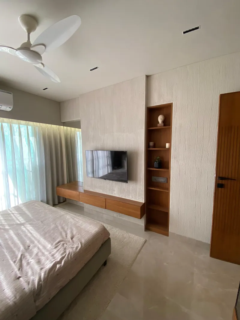 Modern bedroom with floating wood TV console and textured beige accent wall.