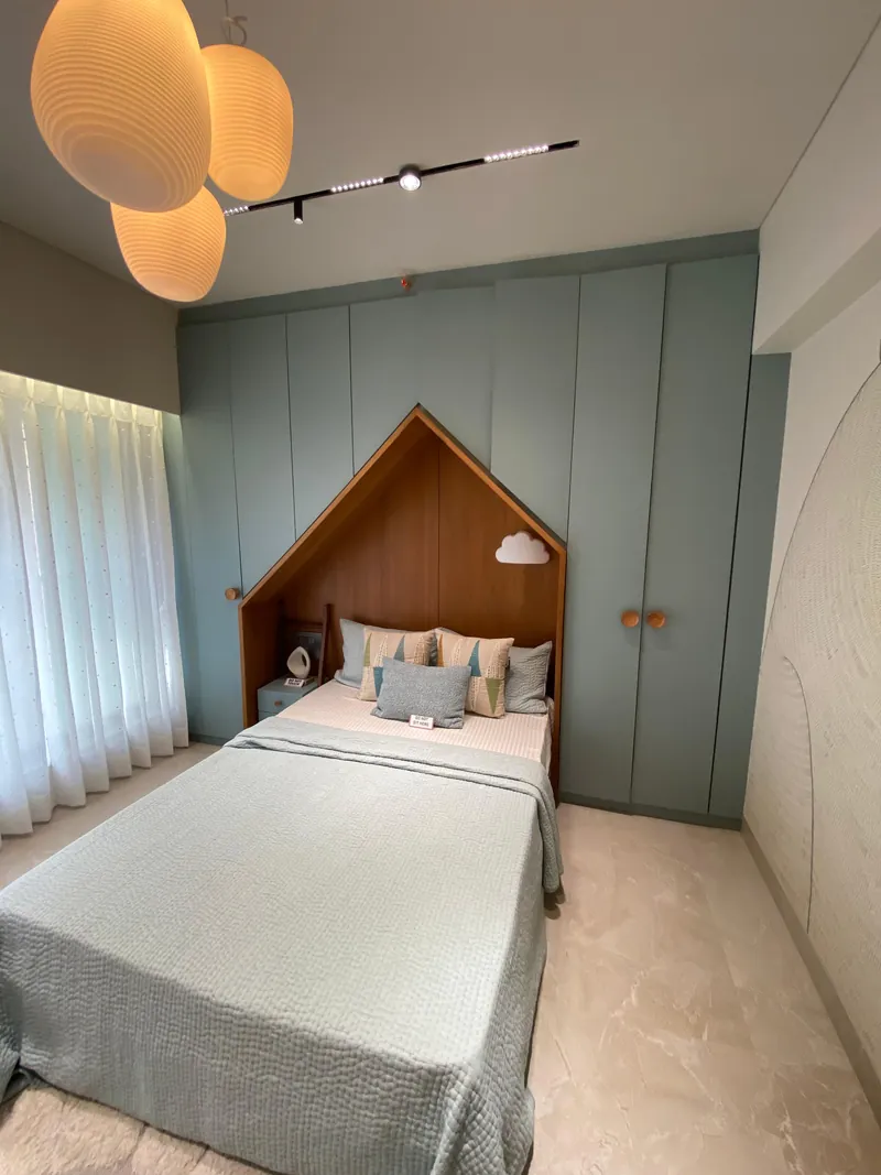 Kids bedroom with house-shaped headboard and sage green built-in wardrobe.