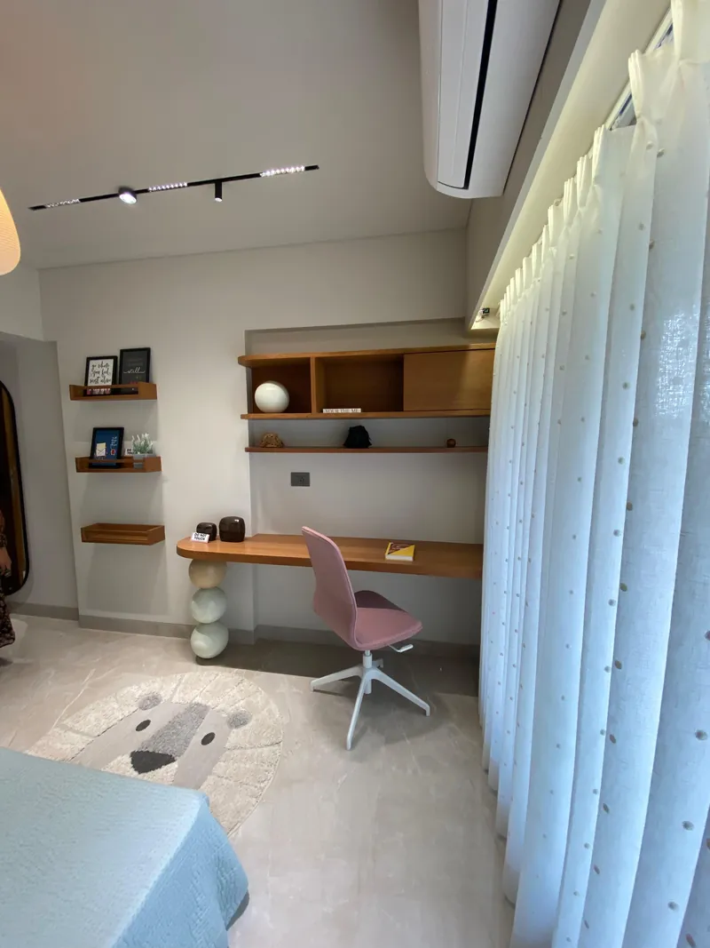 Kids study nook with wooden desk, pink chair and floating shelves.