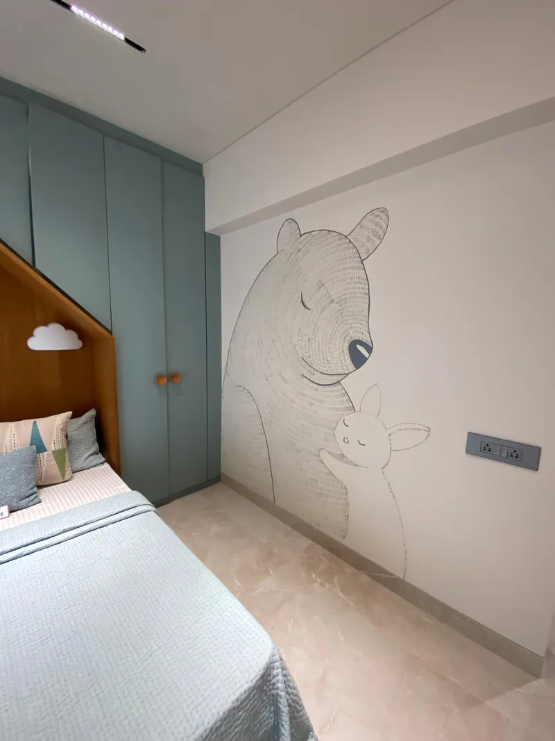 Kids bedroom with a bear-and-rabbit mural and sage green wardrobe.