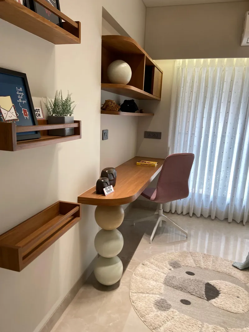 Study corner with wooden floating desk, mauve chair and styled shelves.