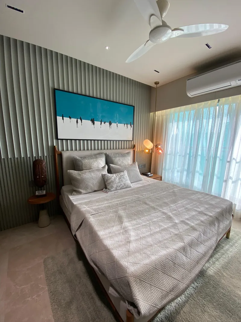 Bedroom with fluted wall, beach artwork and grey upholstered bed.