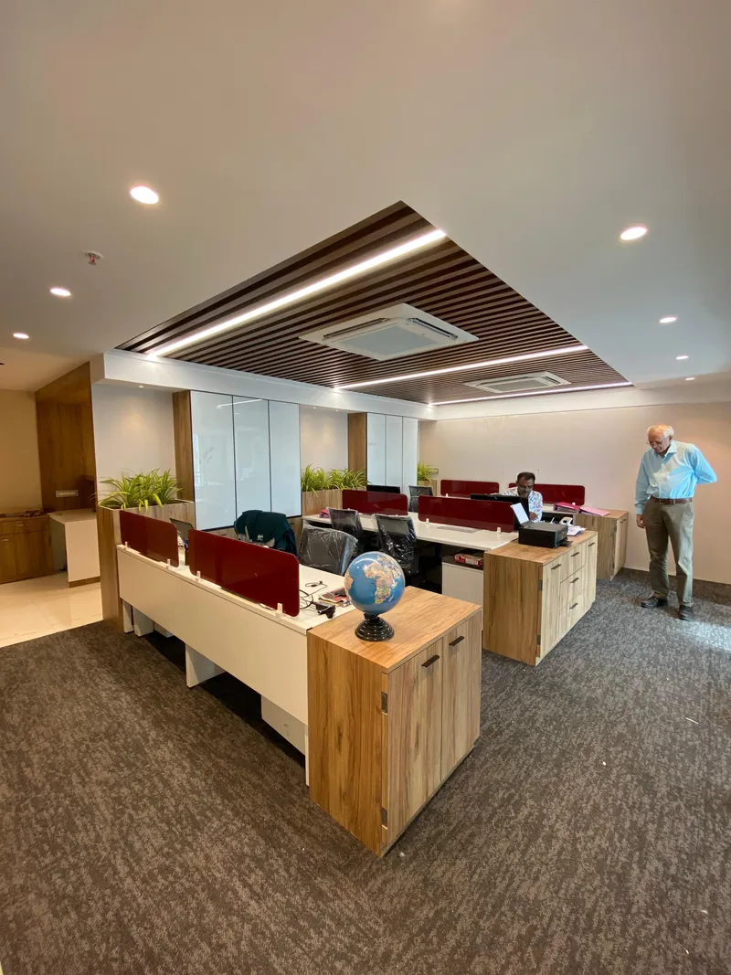 Open office with workstation pods, red dividers and slatted ceiling.