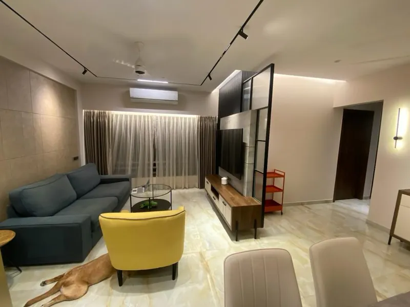 Living room with blue sofa, yellow chair and wooden TV console.