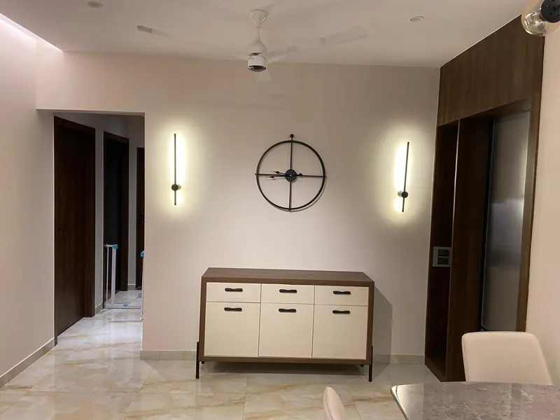 Minimalist hallway with sideboard, wheel clock and linear wall sconces.