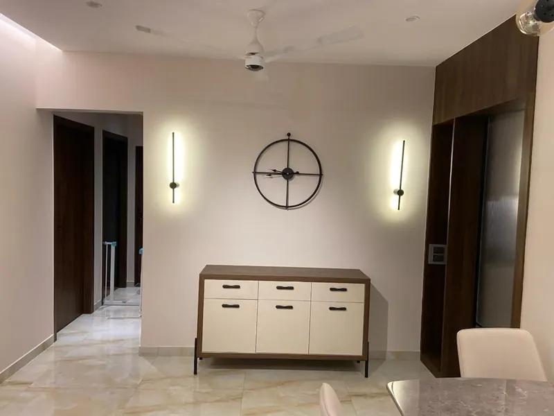 Minimalist dining area with sideboard, wall clock and linear sconces.