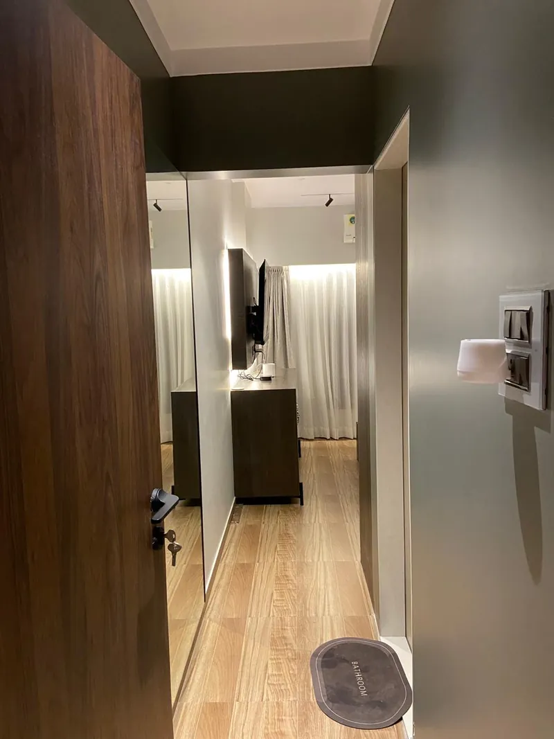 Modern hallway with mirrored wardrobe, wood flooring and dark ceiling.