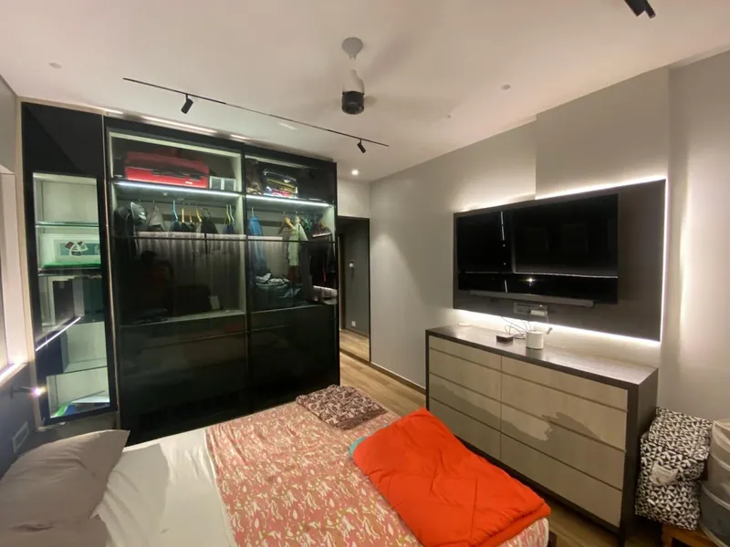 Modern bedroom with glass wardrobe, backlit TV panel and wood dresser.