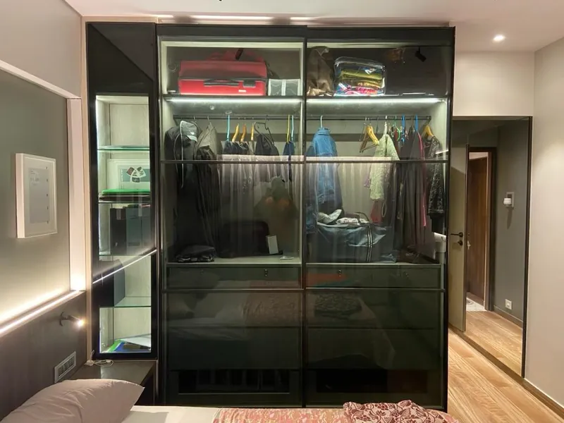 Modern glass-front wardrobe with LED lighting and organized hanging storage.