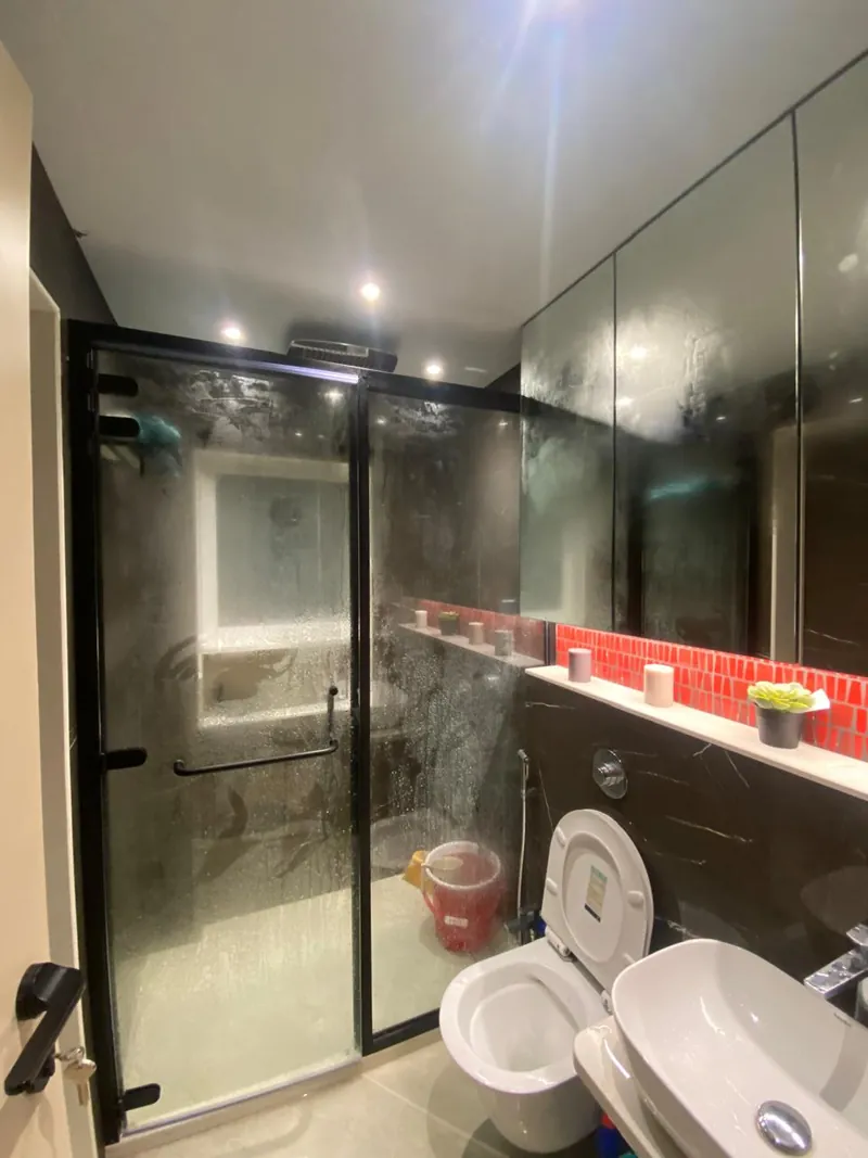 Modern bathroom with glass shower, wall-hung toilet and red mosaic tile accent.