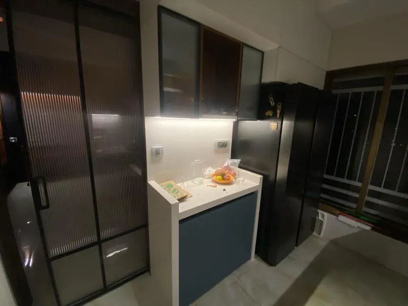 Modern kitchen with fluted glass partition, quartz island and black fridge.