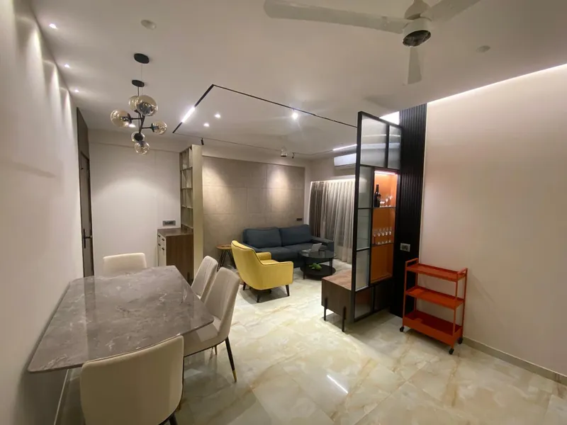 Contemporary open living-dining room with marble table, navy sofa and bar cart.