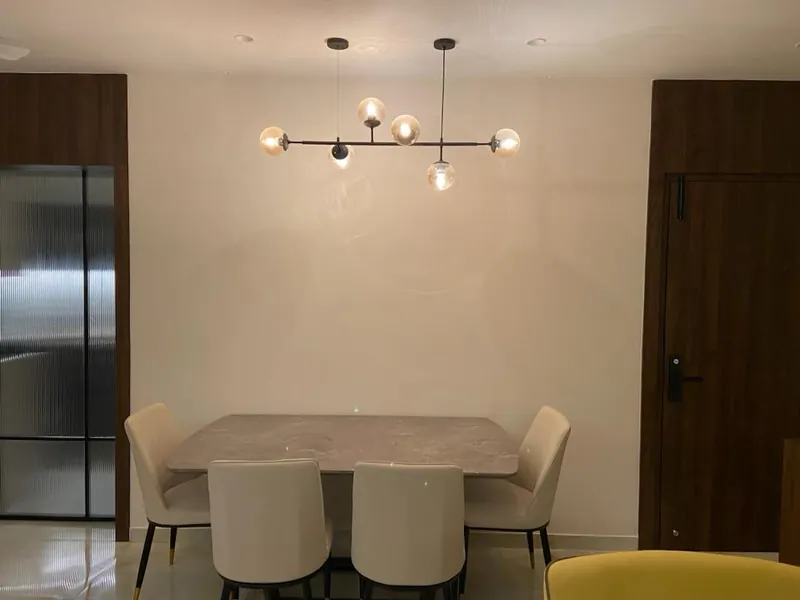 Modern dining area with marble table, white chairs and sputnik pendant light.