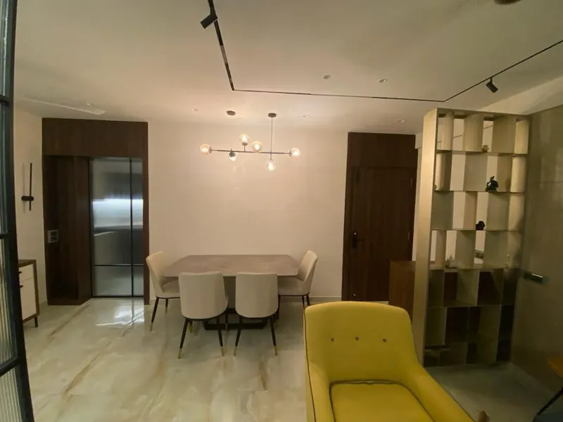 Contemporary dining space with marble table, display shelving and yellow accent chair.