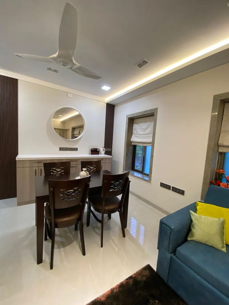 Dining nook with dark wood table, round mirror and built-in sideboard.