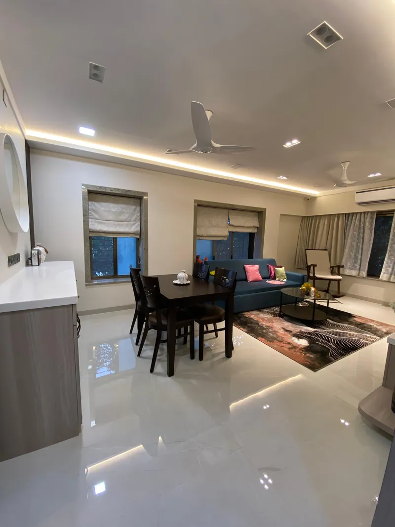 Open living-dining room with teal sofa, patterned rug and glossy floors.